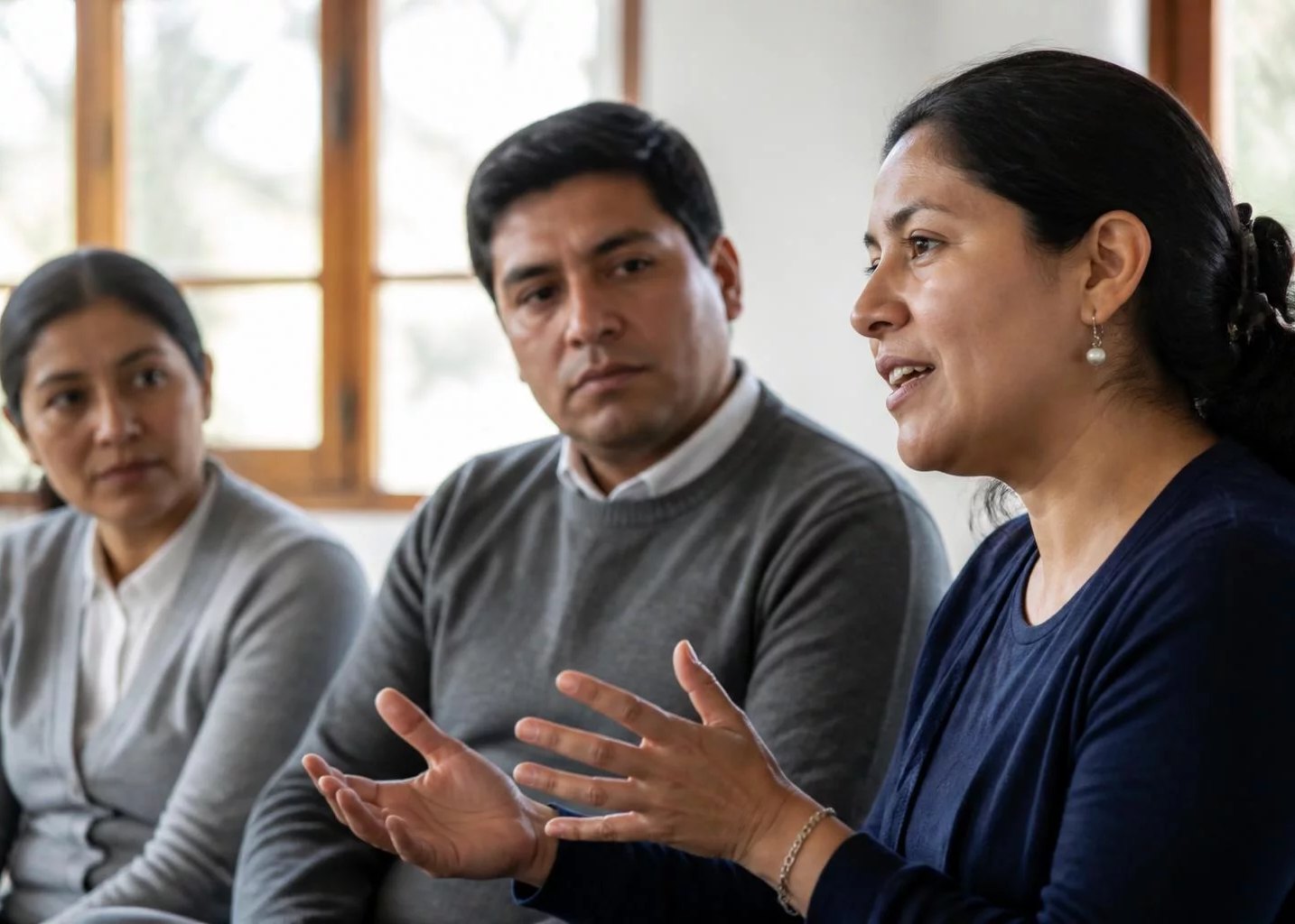 Tres personas en una sala de reuniones, una de ellas argumentando